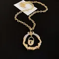 Detailed view of a gold chunky necklace with lock and crystal-studded ring pendant. - Letter Lock Circle Pendant (HN11704) / Gold