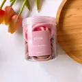 Gros plan d'élastiques à cheveux sans couture roses et marrons dans un flacon de rangement - Série Rose