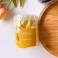 Nahaufnahme gelber nahtloser elastischer Haargummis in einer durchsichtigen Dose mit Etikett - Gelbe Serie