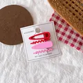 Macro detail of red and pink matte metal hair clips for kids on an accessories card - Red Group