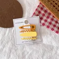 Detail of four yellow and orange gradient metal hair clips on a white display card - Yellow Set