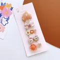 Close-up of four assorted floral and bow fabric hair clips on a pink display card - Orange Pink Mushroom Style