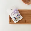 Detalle de pinza floral púrpura y lazo con margaritas sobre una bandeja de madera - Combo de Lazo Floral