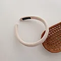 Detailed macro view of beige knitted headband featuring a HAND MADE textile label detail - White