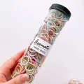 Macro view of macaron colored high elastic hair ties in a clear cylindrical storage tube - Ice Cream Threaded Style