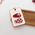 Detail view of handmade red polka dot hair clips set on a display card for kids - Polka Dot Teardrop Set