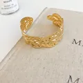 Macro view of a gold-toned open cuff bracelet with an intricate hollow leaf pattern detail - Hollow Feather Texture Style (56#) / Gold