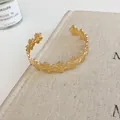 Detailed macro shot of an elegant gold floral open cuff bracelet with hollow petal design - Flower Link Design (86#) / Gold