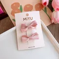 Dettaglio di due fermagli per capelli con fiocco in raso rosa su carta di marca - Fermaglio Con Fiocco Tinta Unita