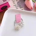 Makroaufnahme von zwei schimmernden Blumenanhängern mit Strass auf rosa Karte - Blumenstil