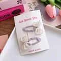 Detailed view of handmade pearl bow hair clips in purple fabric on a display card - Purple
