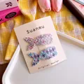 Dettaglio di due fermagli per capelli a coda di sirena glitterati rosa e blu su carta - Set Blu E Viola