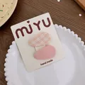 Detalle de pinzas para el cabello en tela a cuadros naranja y rosa en plato de porcelana - Juego Rosa