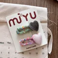 Dettaglio di fermagli per capelli a cuore in velluto e elastici a maglia su carta bianca - Fermagli per Capelli Rosa