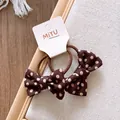 Detailopname van bruine haarelastiekjes met stippen en strik op een kaartje - Bruin Polkadot Strik Stijl