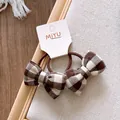 Detail van twee geruite katoenen strik haarelastiekjes op een MIYU displaykaart - Bruin Wit Ruit Strik Stijl