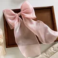 Detail of pink organza oversized bow hair clip with silky texture on dark wood tray - Pink