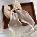 Macro view of a large champagne organza bow hair clip with translucent layered fabric - Champagne
