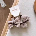 Paire de chouchous nœuds en tissu rose clair avec élastique marron sur carte de support - Style Nœud Plissé Rose