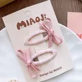 Primer plano de pinzas para el cabello con lazo de tela rosa en un plato blanco - Pinza para el cabello / Rosa