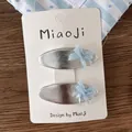 Detail of two silver metal hair clips with light blue mesh bows on a display card - Silver BB Hair Clips
