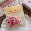 Detail of candy-colored mini bow hair ties in pink shades on a white decorative plate - Gradient Pink