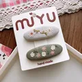 Detailed close-up of handmade floral embroidered fabric hair clips on a card - 4-Grey-Green Floral BB Clip Style
