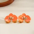 Dettaglio di un fiore in smalto arancione su un bracciale rigido dorato in stile resort. - Orecchini a lobo / Arancione