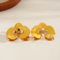 Dettaglio di un bracciale aperto a fiori giallo smaltato con finiture dorate - Orecchini a lobo / Rosa