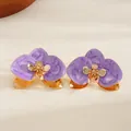 Dettaglio dei fiori in smalto viola marmorizzato su un bracciale rigido dorato aperto. - Orecchini a lobo / Viola