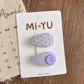 Detail von lila gepunkteten Stoff-Haarspangen mit Knopf auf weißer Displaykarte - Hellviolett