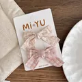 Dettaglio di due fermagli per capelli in tessuto a fiori e a quadretti su carta espositiva - Combinazione Floreale E A Quadri Rosa / Fiocco Rosa