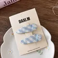 Dettaglio di fermagli per capelli a quadretti blu con fiocchi e perline su carta - Clip BB a Maglia Goccia