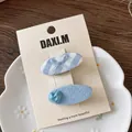 Dettaglio di fermagli per capelli blu con fiocco a scacchi e cuore su piatto di ceramica - Clip a Becco d'Anatra Cuore