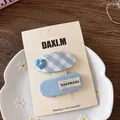 Dettaglio di fermagli per capelli a quadretti blu e etichetta fatta a mano nel piatto - Clip BB a Maglia Cuore