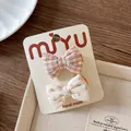 Close-up of handmade floral and plaid fabric bow hair clips set on a display card - Light Orange