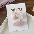 Close-up of pink floral bow hairclip and plaid oval hairpin set on card packaging - 2-Floral Bow Style