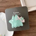 Close-up of sparkling green star hair clips with pink bows on a branded card - Mint Green