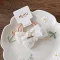 Dettaglio di due elastici per capelli in pizzo bianco con perle su cartoncino - Stile Pizzo con Perle / Elastico con Perle e Pizzo