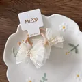 Dettaglio di elastici per capelli con fiocco in tulle beige e pizzo su piatto fiorito - Stile Decorativo in Pizzo Organza / Elastico in Chiffon Beige