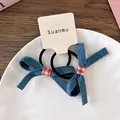 Détail de chouchous en denim avec nœud vichy rouge sur une assiette en céramique - Élastique à Nœud Plaid