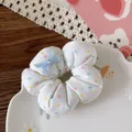 Detailed view of a white floral scrunchie with a blue ribbon bow on a decorative plate - 3-Heart Polka Dot Style