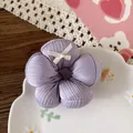 Dettaglio di un elastico a fiori viola con fiocco bianco su un piatto a nuvola - 5-Stile Viola