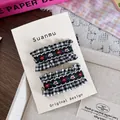 Details von zwei bestickten Gingham-Haarspangen auf einem dekorativen Spitzenhintergrund - S&W Kariert Spitze