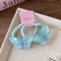 Gros plan sur élastiques papillon en résine bleue avec pois colorés sur ruban tissé - Pois bleus