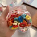Close-up of colorful mini elastic hair ties stored in a clear container for girls - Rainbow