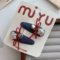 Détail de barrettes en denim avec nœuds rouges et breloques cœur argentées - Style Pendentif Étoile (Lot de 2)