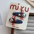 Détail de barrettes en denim avec nœuds rouges et breloques cœur sur carte support - Style Pendentif Cœur (Lot de 2)