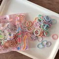 Detail of candy-colored elastic hair ties in a cute cartoon package on a wooden desk - Candy Bean Style