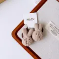 Close-up of brown plush bunny hair ties with white pearls and textured knit fabric - Small Rabbit Style